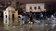People wade through a square after a flash flood in Safi on December 14, 2025. Flash-flooding caused by sudden, heavy rain killed at least 21 people in the Moroccan coastal town of Safi on December 14, local authorities said. (Photo by AFP)