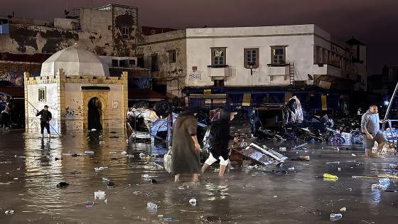 People wade through a square after a flash flood in Safi on December 14, 2025. Flash-flooding caused by sudden, heavy rain killed at least 21 people in the Moroccan coastal town of Safi on December 14, local authorities said. (Photo by AFP)